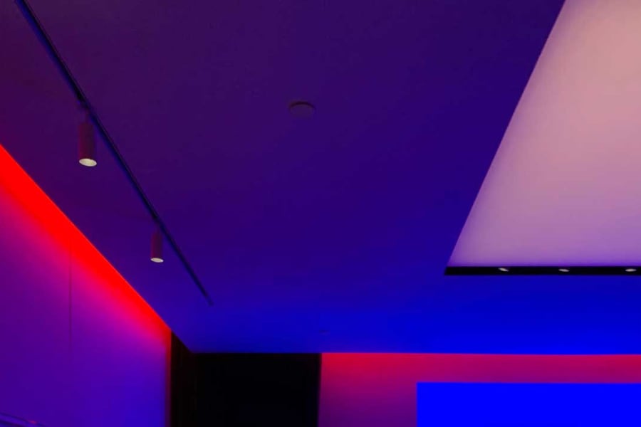 A ceiling corner cast in red and purple lighting.