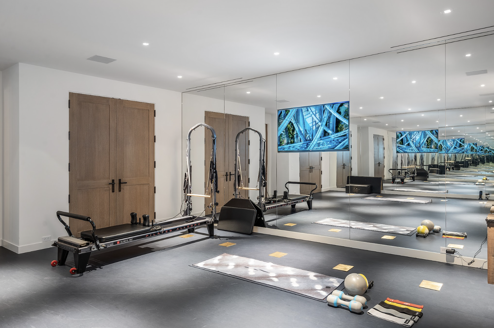 An empty workout room contains pilates equipment and a mat with weights.